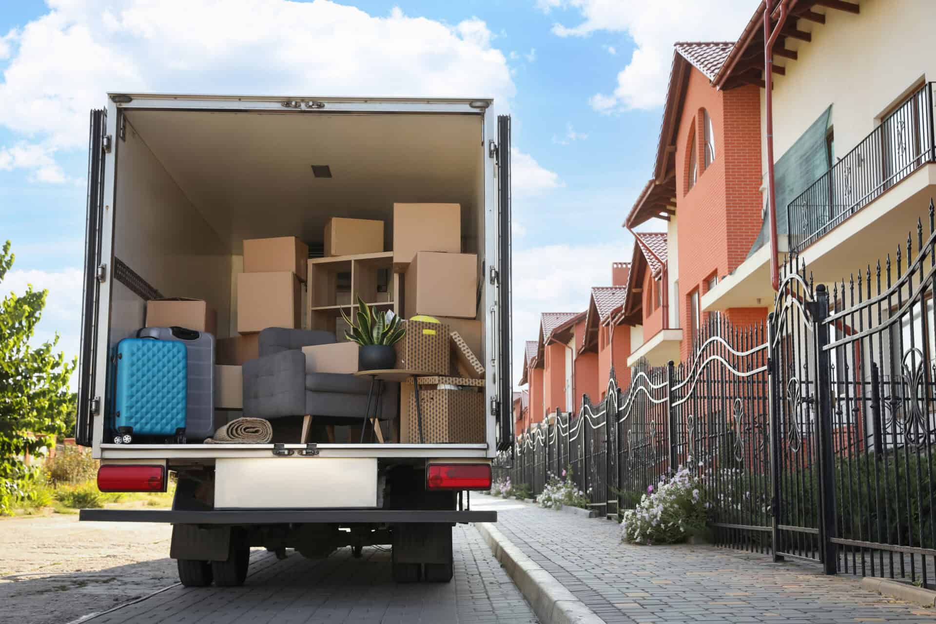 Removal van loaded with moving boxes and furniture outside a home